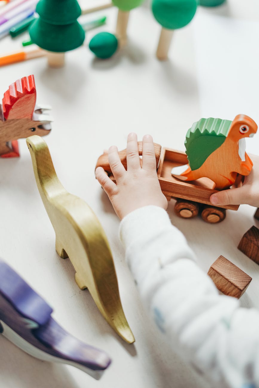 person holding brown wooden animal figurine