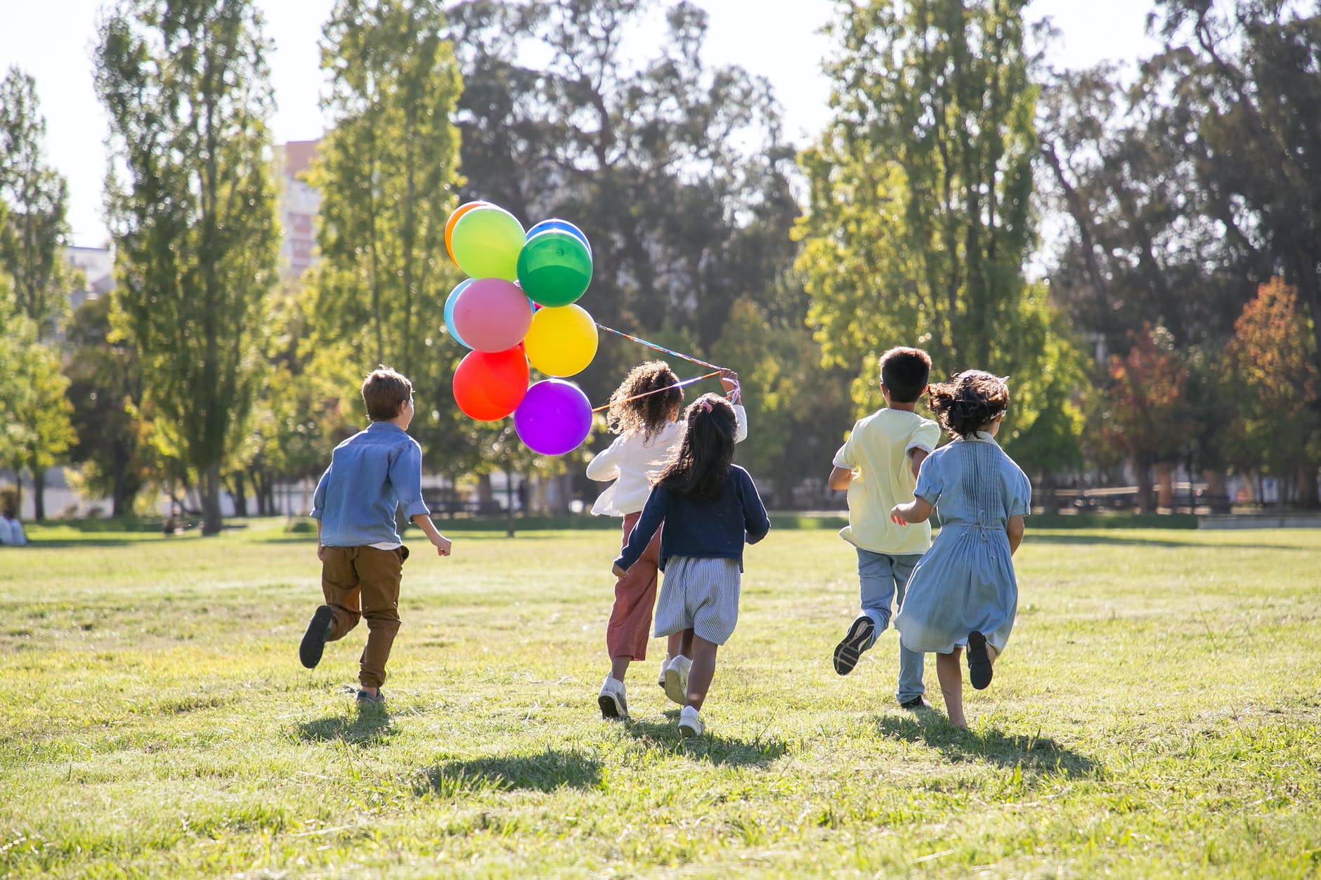 children playing with balloons on green grass field